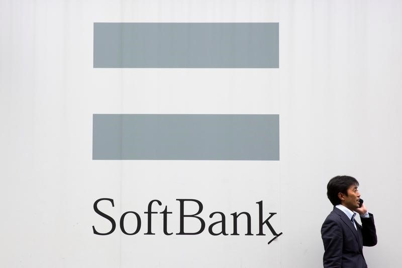 © Reuters. A man talks on the phone as he stand in front of an advertising poster of the SoftBank telecommunications company in Tokyo
