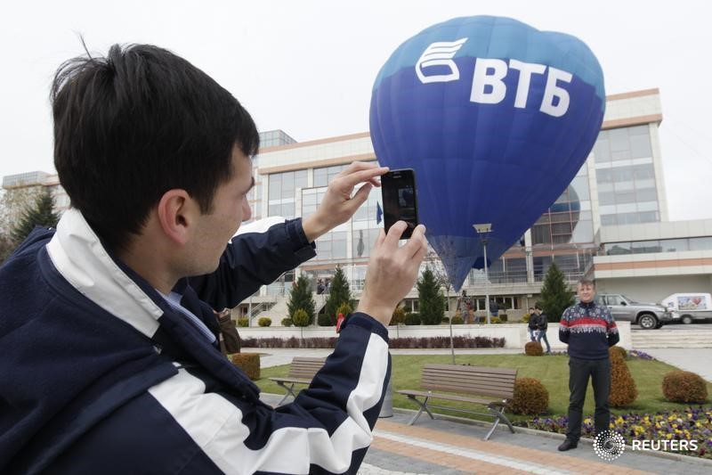 © Reuters. Люди фотографируются на фоне воздушного шара с логотипом ВТБ в Ессентуках