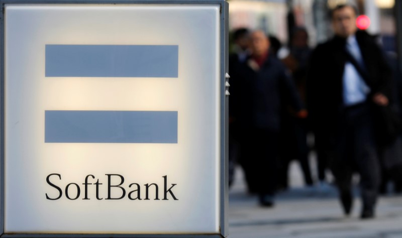 © Reuters. People walk behind the logo of SoftBank Corp in Tokyo