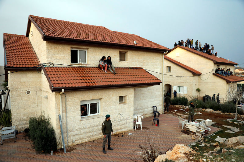 © Reuters. Pro-settlement activists sit on a rooftop of a house to resist evacuation of some houses in the settlement of Ofra in the occupied West Bank, during an operation by Israeli forces to evict the houses