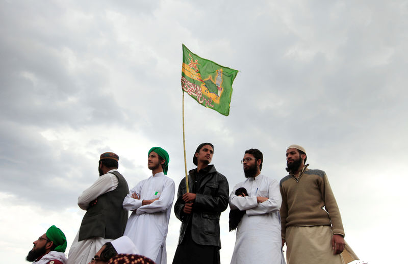 © Reuters. A man holds a religious flag as he attends with other a gathering to mark the anniversary of Mumtaz Qadri death next to the shrine built over his grave outside Islamabad