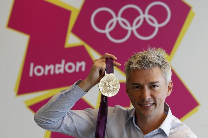 © Reuters. Britain's Olympic triple jump gold medalist Jonathan Edwards, poses for a photograph with a gold medal designed for the London 2012 Olympic Games in London