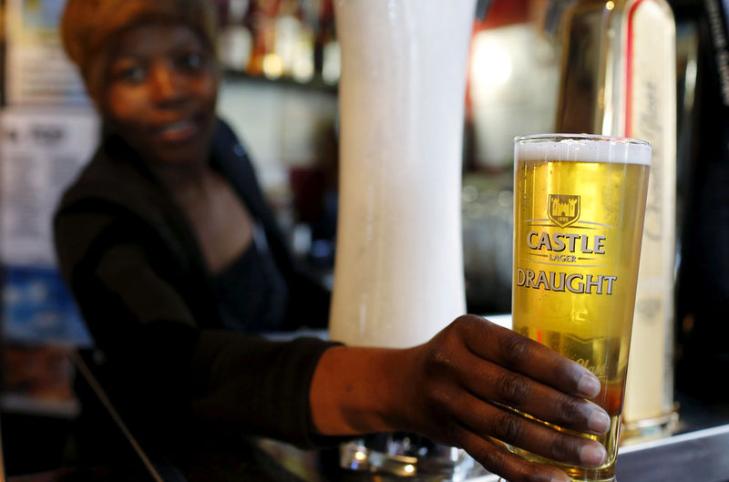 © Reuters. FILE PHOTO -  A bartender serves a beer produced by brewing company SAB Miller at a bar in Cape Town