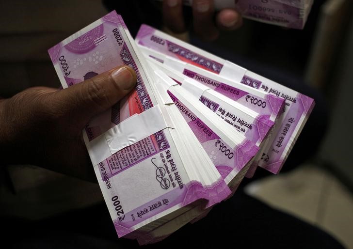 © Reuters. FILE PHOTO: A cashier displays the new 2000 Indian rupee banknotes inside a bank in Jammu