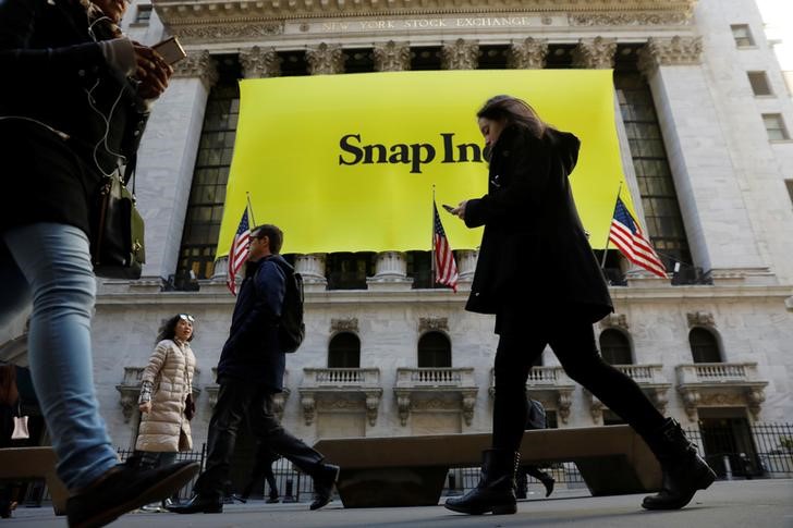 © Reuters. Pedestrians walk past the front of the New York Stock Exchange (NYSE) with a Snap Inc. logo hung on the front of it shortly before the company's IPO in New York