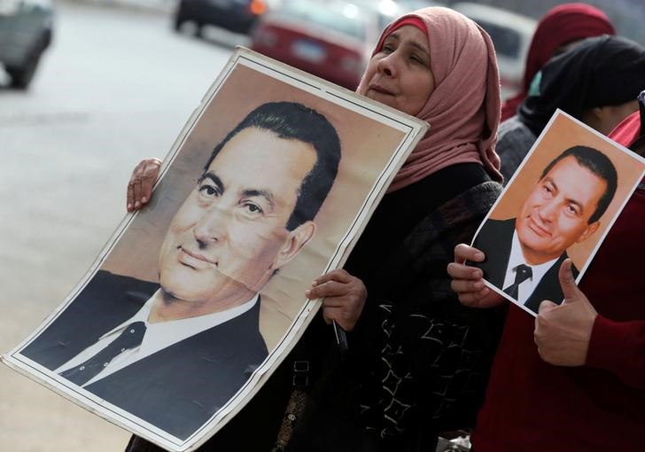 © Reuters. Simpatizantes mostram fotos de Hosni Mubarak enquanto aguardam transferência do ex-presidente egípcio para tribunal