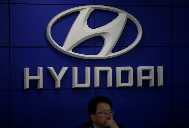 © Reuters. An employee sits in front of the logo of Hyundai Motor at its dealership in Seoul