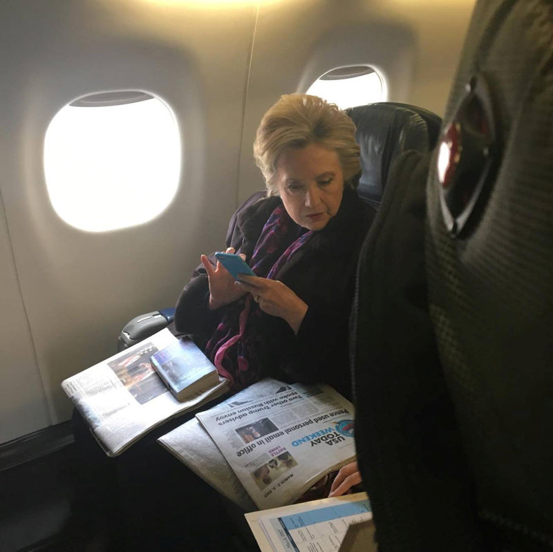 © Reuters. Hillary Clinton looks at a newspaper carrying an article about Vice President Mike Pence's use of personal email