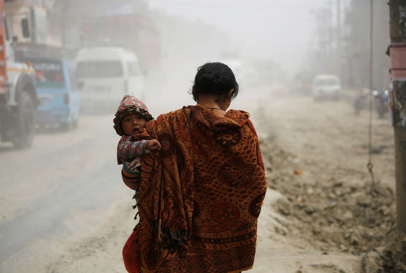 © Reuters. Mulher carrega criança em rua de Catmandu, no Nepal