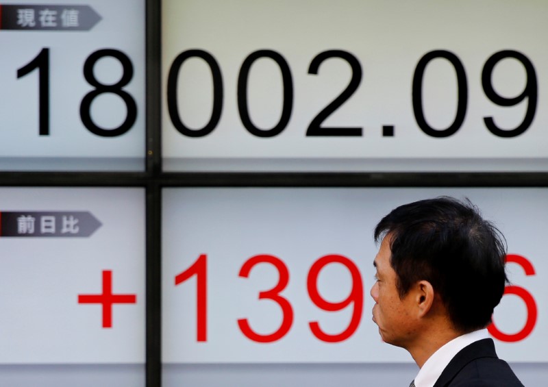 © Reuters. Man walks past an electronic board showing Japan's Nikkei average outside a brokerage in Tokyo