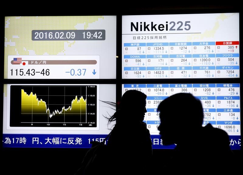 © Reuters. Pedestrians walk past electronic boards showing the graphs of the recent fluctuations of the Japanese yen's exchange rate against the U.S. dollar and the various stock prices outside a brokerage in Tokyo