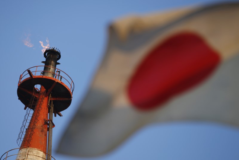 © Reuters. A Japanese national flag flutters near a chimney emitting fire at an oil refinery in Kawasaki, near Tokyo