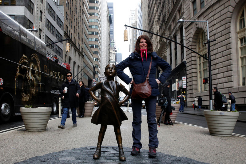 © Reuters. Mulher posa ao lado de estátua de menina encarando o Touro de Wall Street, em Nova York