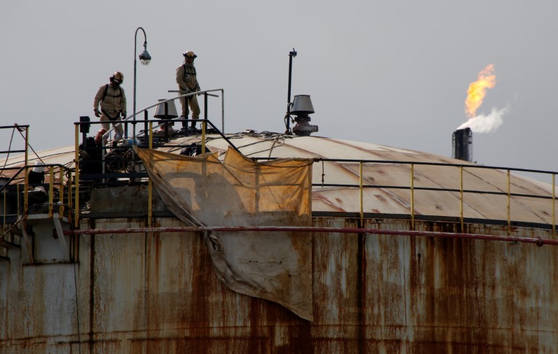 © Reuters. Workers are seen on a tank at a factory at the Keihin industrial zone in Kawasaki