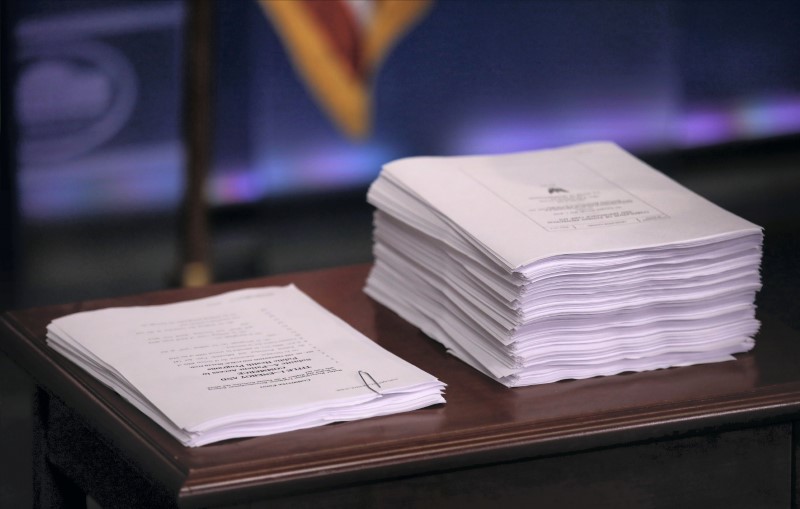 © Reuters. Repeal and replace recommendations produced by Republicans in U.S. House sit next to the Affordable Care Act at White House briefing