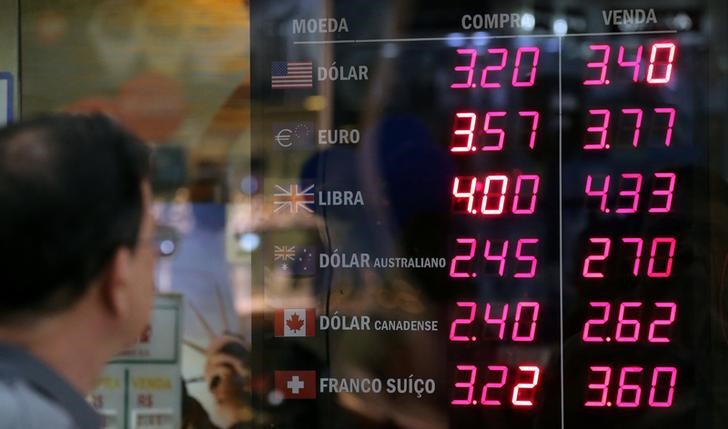 © Reuters. Man observes a board showing the Brazilian Real-U.S. dollar and several other foreign currencies exchange rates in Rio de Janeiro