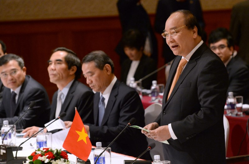 © Reuters. Vietnamese Prime Minister Nguyen Xuan Phuc (R) delivers a speech at the Vietnam-Japan Business forum also attended by Japanese Prime Minister Shinzo Abe (not pictured) in Hanoi