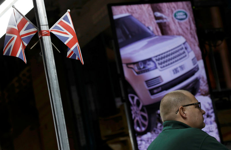 © Reuters. FILE PHOTO: A worker stands under Union Flags at the Jaguar Land Rover facility in Solihull