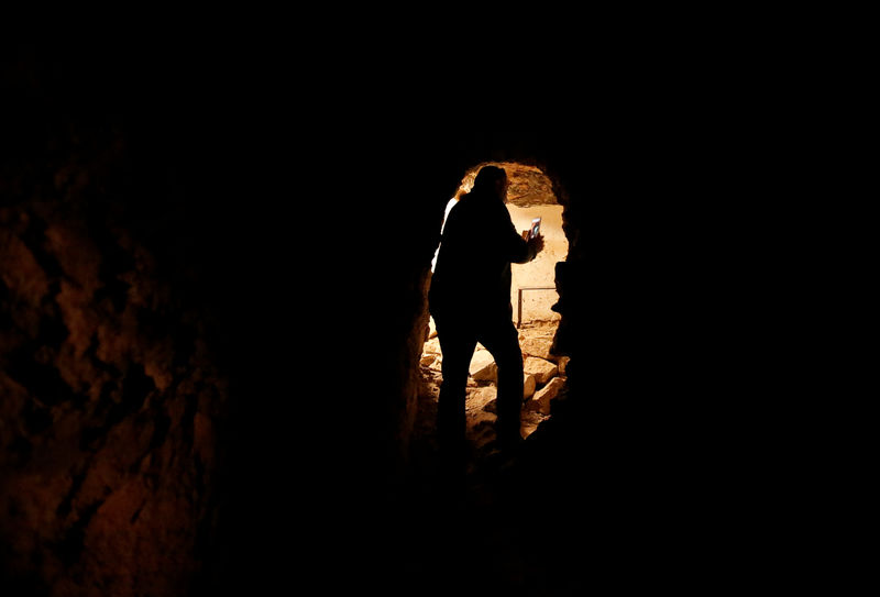 © Reuters. A man takes pictures of artefacts and archaeological pieces in a tunnel network running under the Mosque of Prophet Jonah, Nabi Yunus in Arabic, in eastern Mosul