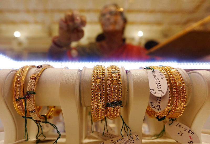 © Reuters. FILE PHOTO: Gold bangles are on display as a woman makes choices at a jewellery showroom during Dhanteras, a Hindu festival associated with Lakshmi, the goddess of wealth, in Kolkata, India