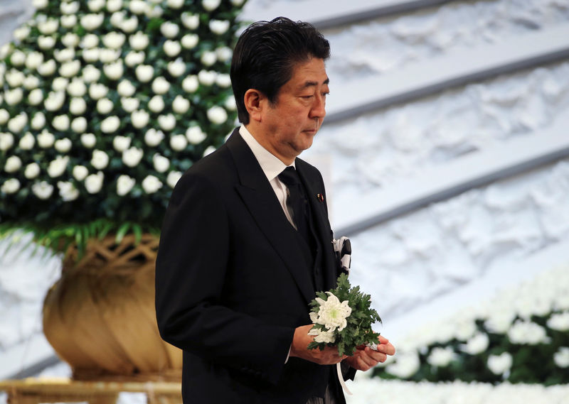 © Reuters. Japanese Prime Minister Shinzo Abe holds a chrysanthemum to offer for the victims of the March 11, 2011 earthquake and tsunami during the national memorial service in Tokyo