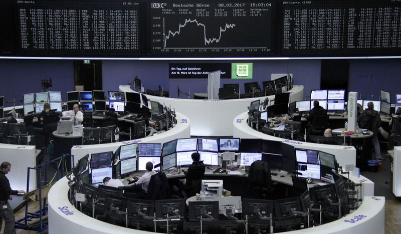 © Reuters. Traders work at their desks in front of the German share price index DAX board in Frankfurt