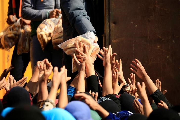 © Reuters. Iraquianos que fugiram de casa durante batalha contra Estado Islâmico recebem pão em acampamento ao sul de Mosul