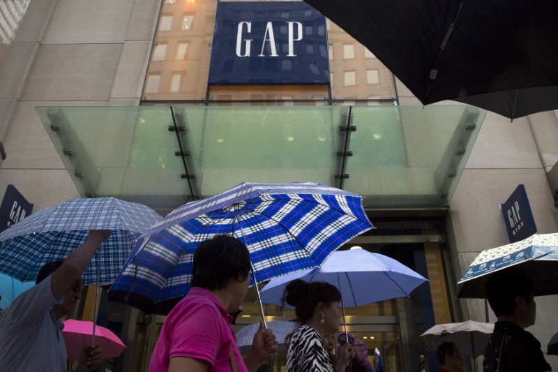 © Reuters. People carrying umbrellas pass by a Gap store on 5th avenue in midtown Manhattan in New York