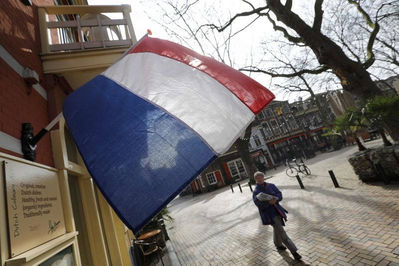 © Reuters. A woman walks past a national flag the day before a general election in Delft in the Netherlands