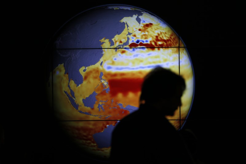 © Reuters. A woman walks past a map showing the elevation of the sea in the last 22 years during the World Climate Change Conference 2015 at Le Bourget