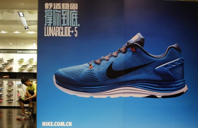 © Reuters. A customer tries on a pair of Nike's shoes inside a shop at a shopping district in Beijing