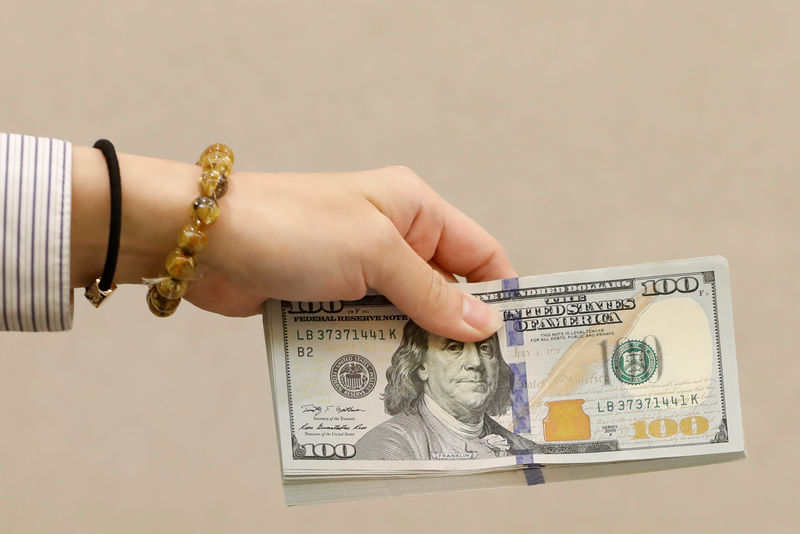 © Reuters. FILE PHOTO: A teller holds U.S. $100 dollar at a bank in Taipei, Taiwan