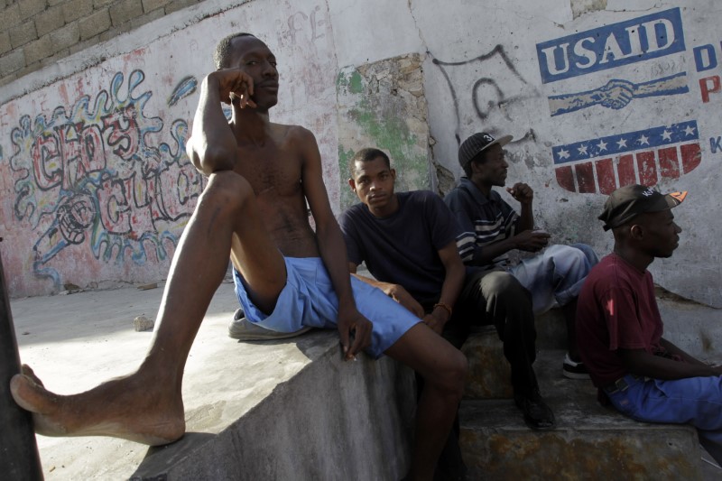 © Reuters. Haitians sit in a street next to a logo of USAID (United States Agency International Development) in downtown Port-au-Prince