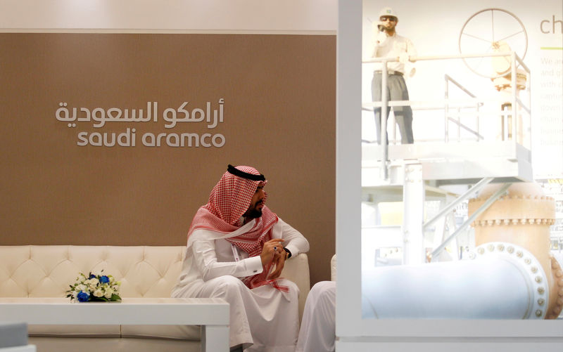 © Reuters. FILE PHOTO: A Saudi Aramco employee sits in the area of its stand at the Middle East Petrotech 2016 in Manama