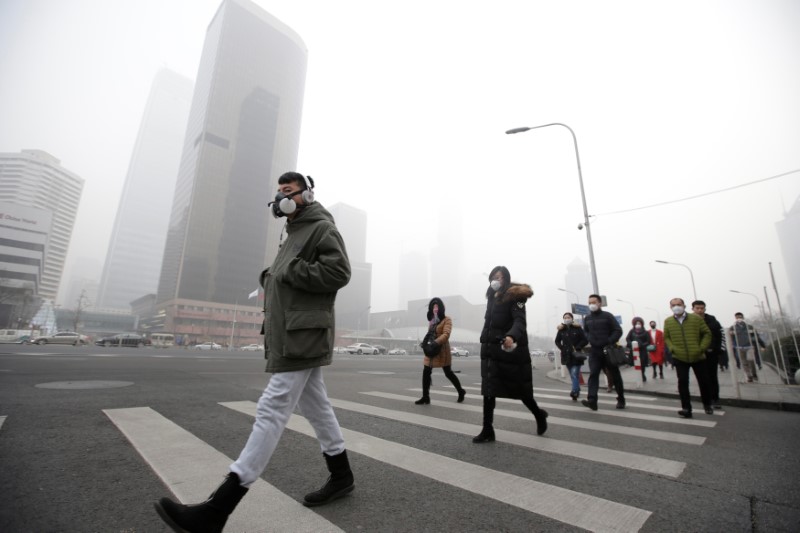 © Reuters. A man wearing a respiratory protection mask walks toward an office building during smog in Beijing