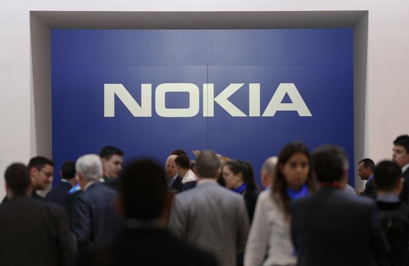 © Reuters. Visitors stand next to a logo of Nokia at Mobile World Congress in Barcelona