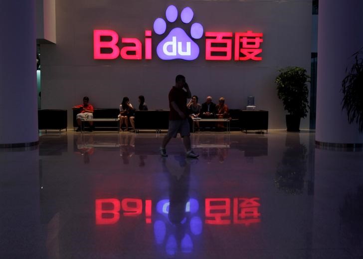 © Reuters. Funcionário usa seu telefone móvel enquanto anda em frente ao logotipo da companhia de Baidu em sua sede em Pequim