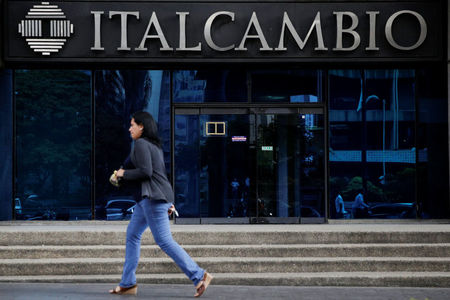 © Reuters. A woman walks past a branch of Italcambio currency exchange in Caracas