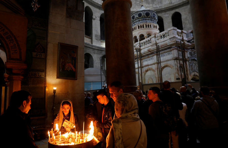 © Reuters. Worshippers light candles as the newly restored Edicule is seen in the background at the Church of the Holy Sepulchre in Jerusalem's Old City