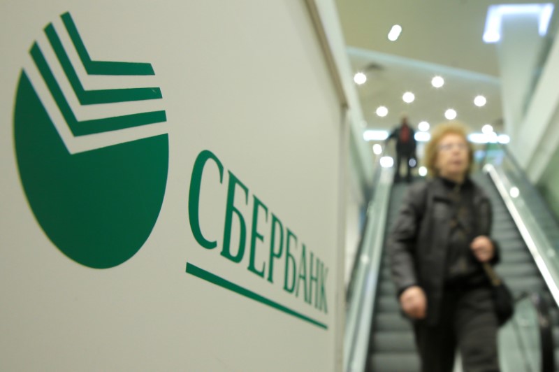 © Reuters. People walk down stairs past logo of Sberbank at its branch in Moscow