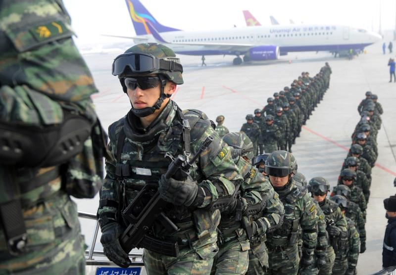 © Reuters. Paramilitary policemen board a plane as they head for an anti-terrorism oath-taking rally in Kashgar, from Urumqi