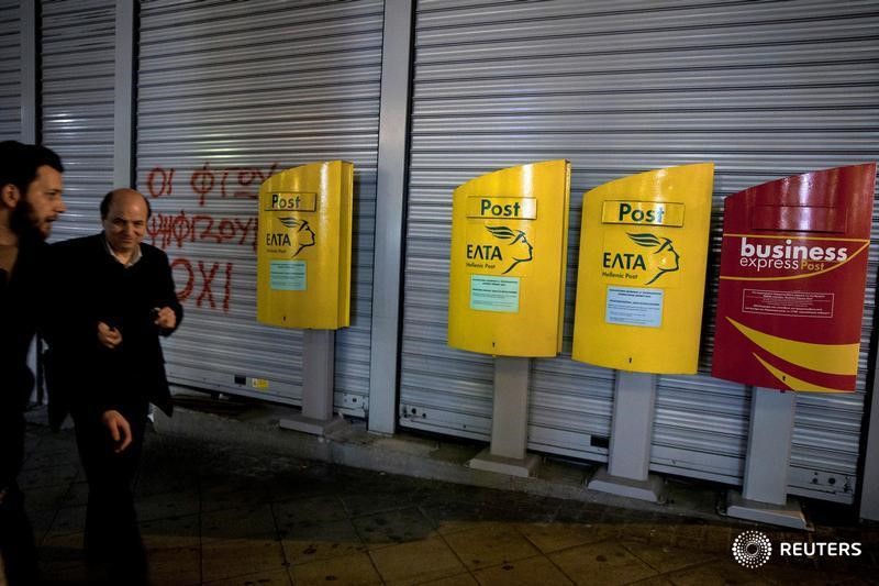 © Reuters. People make their way past mailboxes outside a closed Hellenic Post branch in Athens