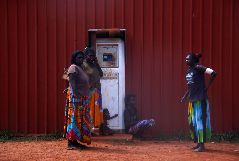 © Reuters. FILE PHOTO: Members of the Australian Aboriginal community of Ramingining stand next to a machine used to pay for fuel in East Arnhem Land, located east of the Northern Territory city of Darwin