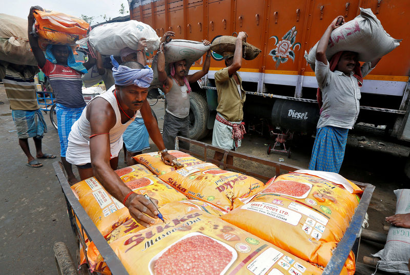 © Reuters. FILE PHOTO: A labourer marks the sacks filled with pulses before loading them into a truck as others wait in a queue to load at a wholesale market in Kolkata