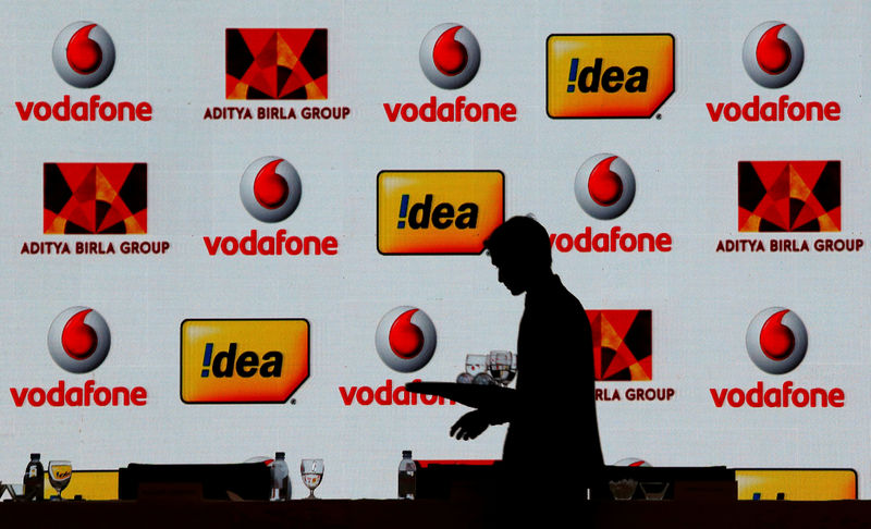 © Reuters. A hotel employee clears a table after Vodafone Group and Idea Cellular news conference in Mumbai