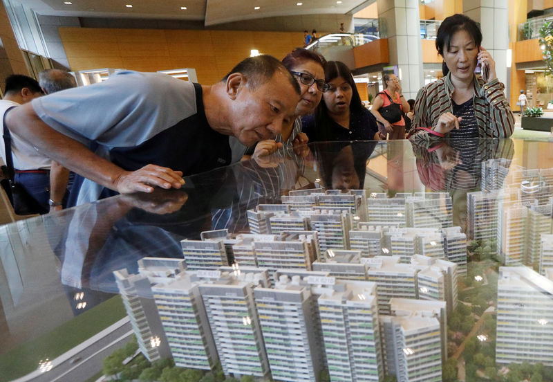 © Reuters. FILE PHOTO - Potential buyers look at models of a new public housing estate to be constructed in Singapore