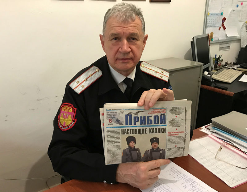 © Reuters. Russian Cossack commander Bagliy shows local newspaper with picture of his fellow Cossack Sokalsky killed near Palmyra, in Gelendzhik