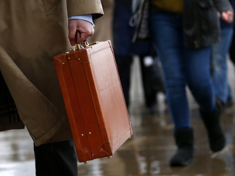 © Reuters. A worker holds his briefcase as he walks across London Bridge in London