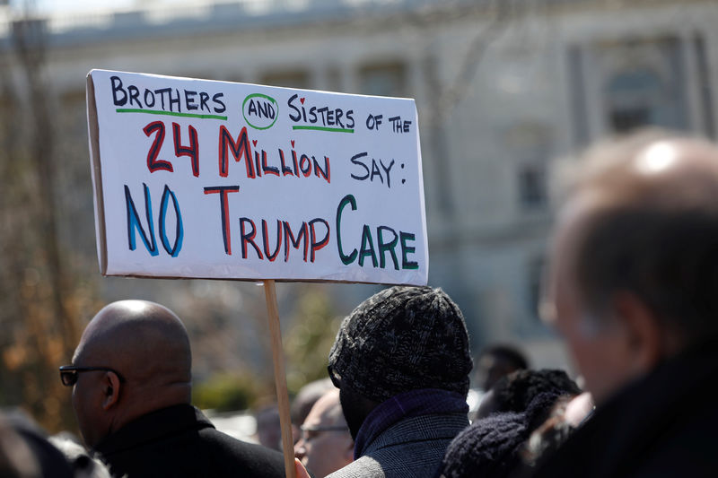 © Reuters. Demonstrators hold signs during a protest against the repeal of the Affordable Care Act outside the Capitol Building in Washington