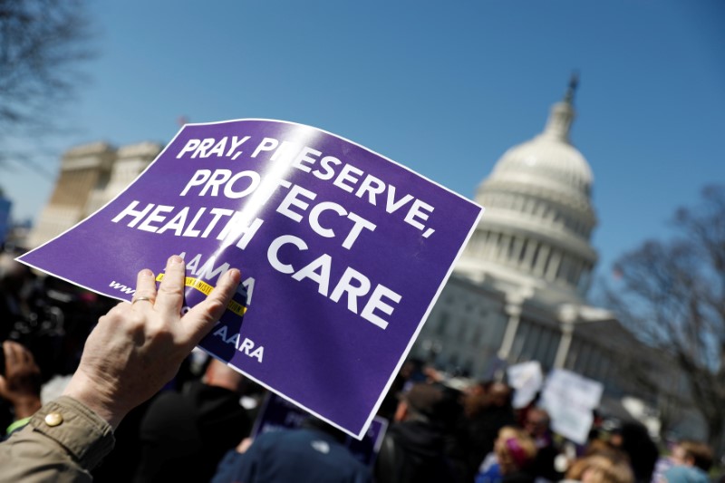 © Reuters. Demonstrators hold signs during a protest against the repeal of the Affordable Care Act outside the Capitol Building in Washington